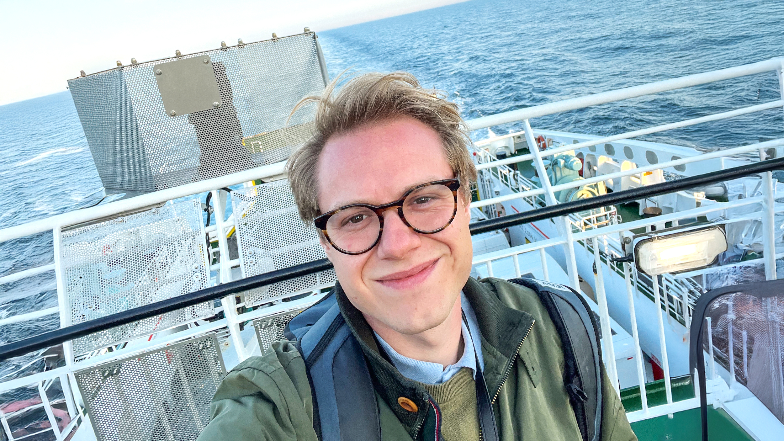 Ein Selife eines blonden Mannes auf dem Deck eines Schiffes.
