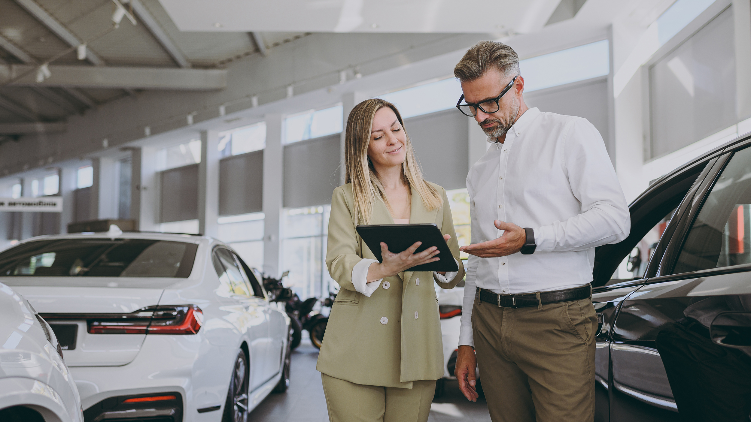 Eine Frau und ein Mann gehen in einem Autohaus Unterlagen durch