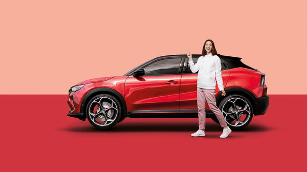 Eine Frau steht vor einem roten Auto