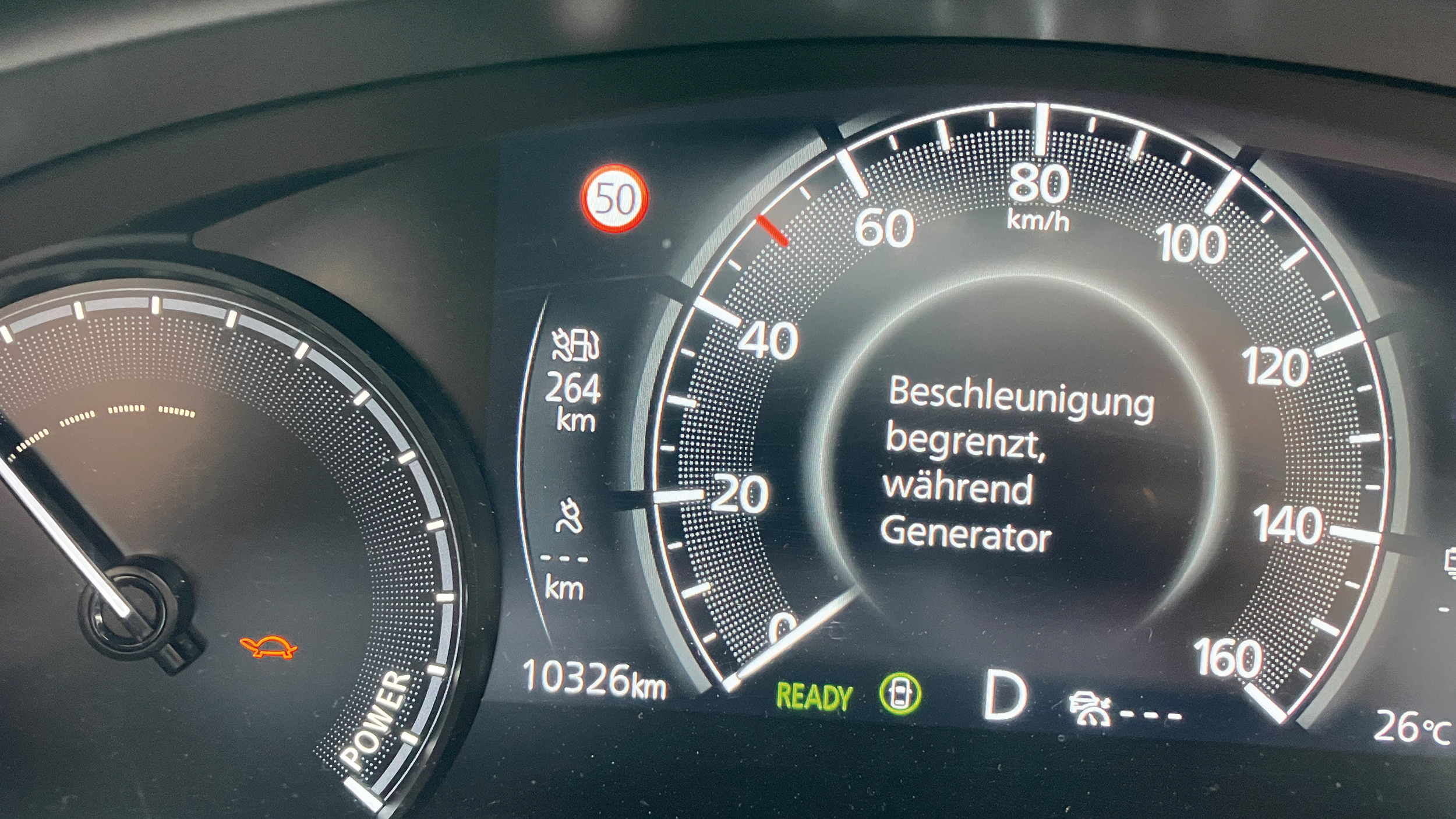Tachometer eines Mazda MX-30, auf dem ein orangenes Schildkröten-Symbol sowie die Information, das die Beschleunigung begrenzt ist, angezeigt wird.
