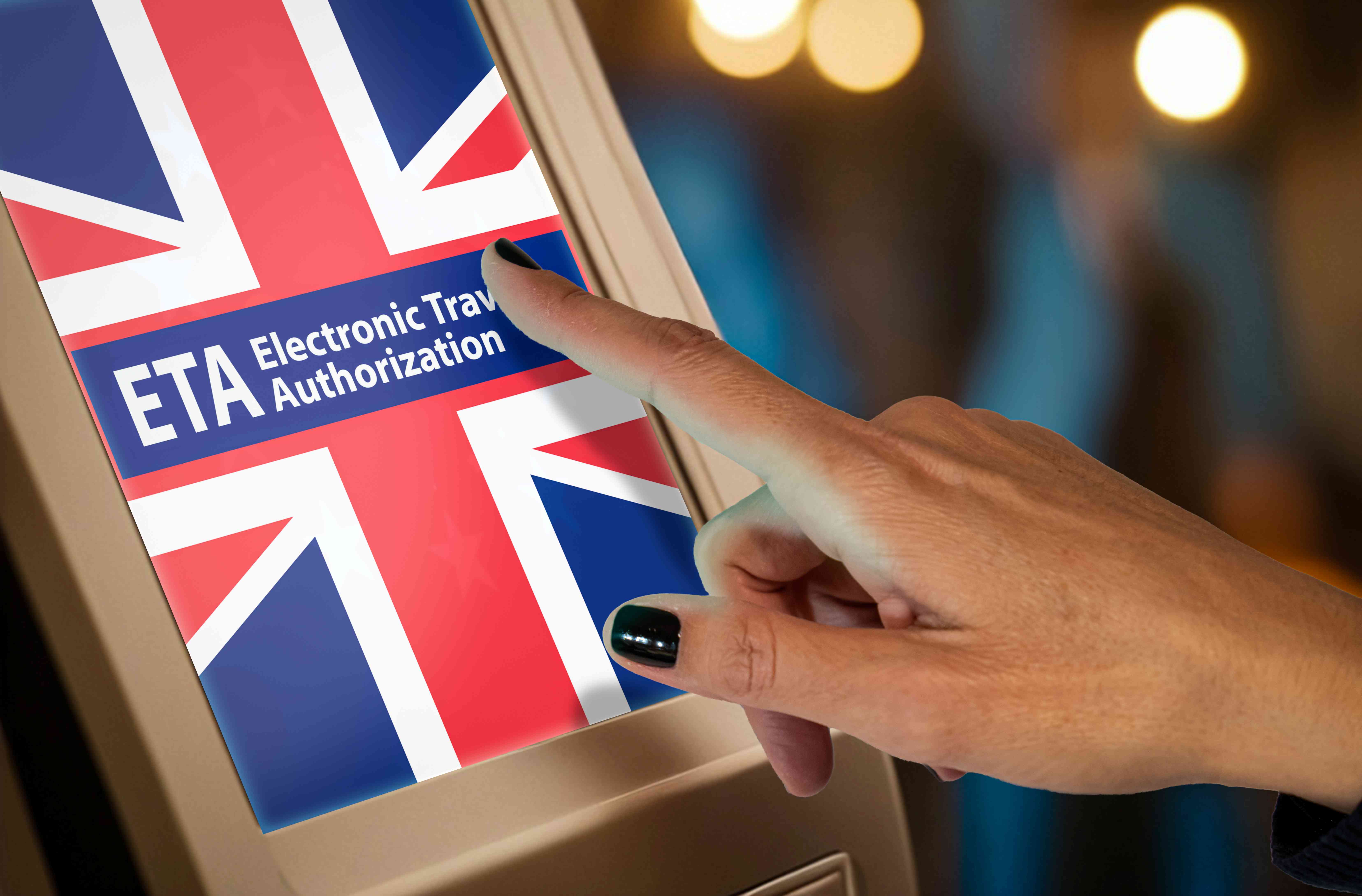 Ein Bildschirm, der eine britische Flagge mit dem Schrifzug ETA Electronic Travel Authorization zeigt, und eine Hand, die den Bildschirm berührt