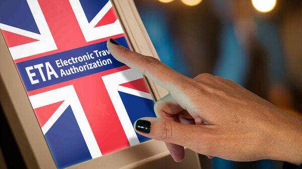 Ein Bildschirm, der eine britische Flagge mit dem Schrifzug ETA Electronic Travel Authorization zeigt, und eine Hand, die den Bildschirm berührt