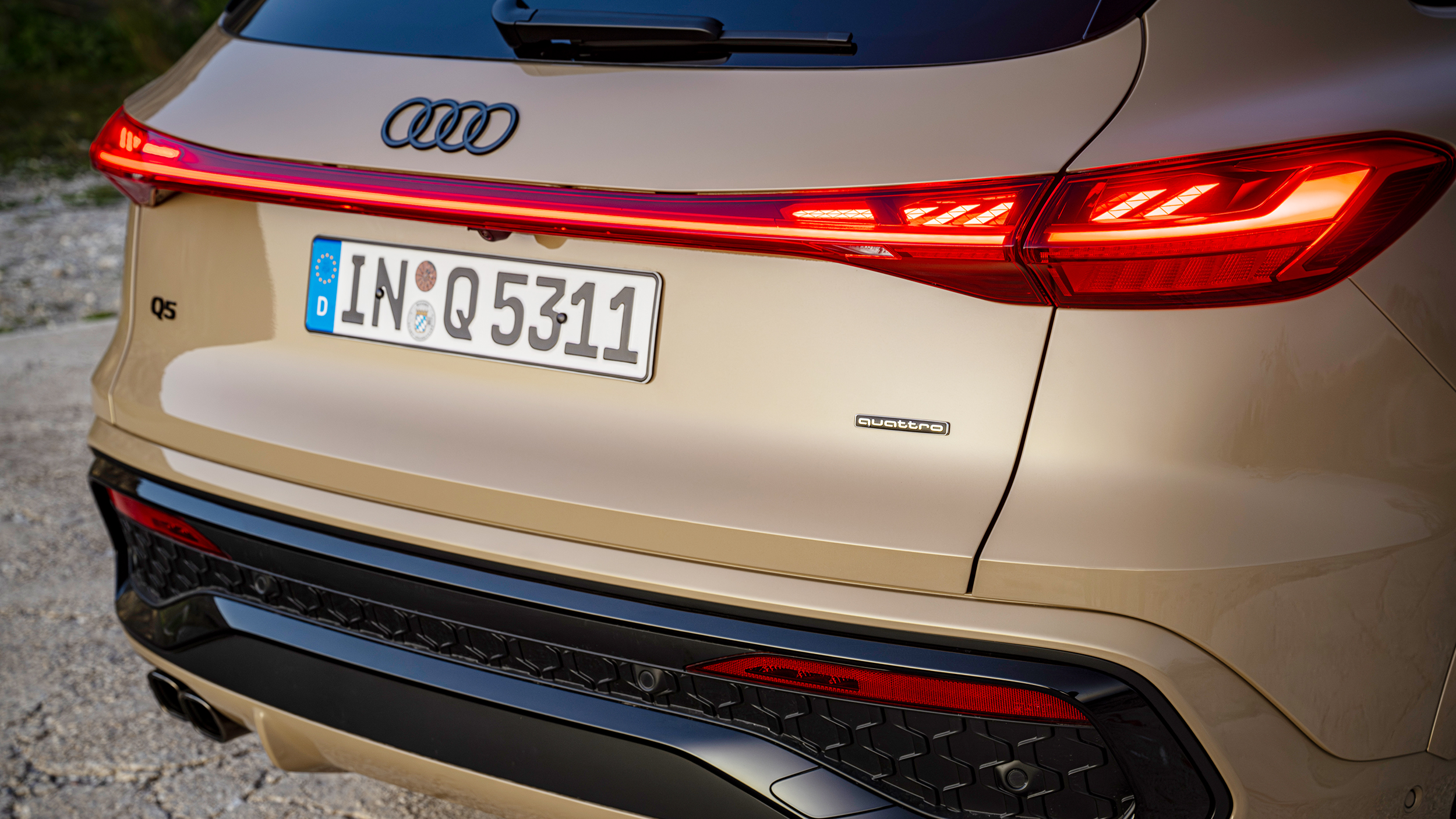 Das Heck eines beigen Audi Q5 mit durchgehendem Leuchtenband.