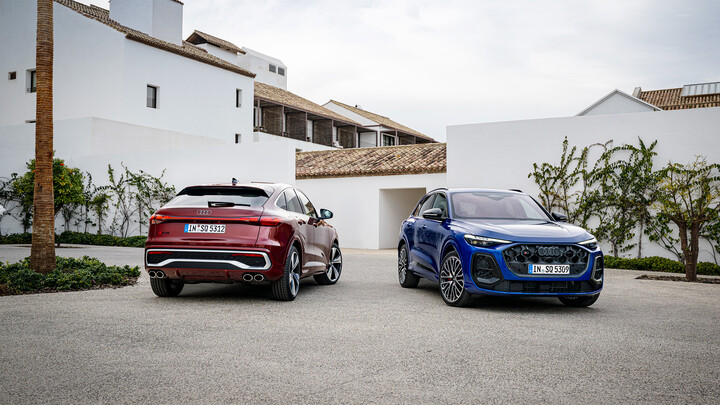 Ein roter und ein blauer Audi Q5 stehen vor einem weißen Gebäudekomplex.