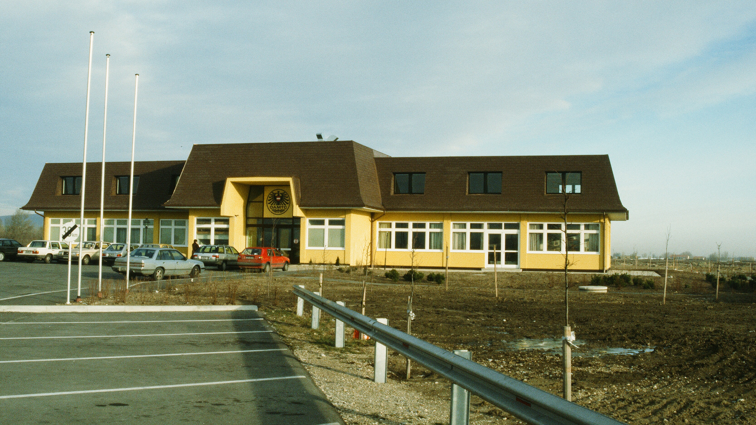 Ein großes gelbes ÖAMTC-Gebäude, Parkplätze und Autos. Das war das erste Gebäude des Fahrtechnikzentrums in Teesdorf.