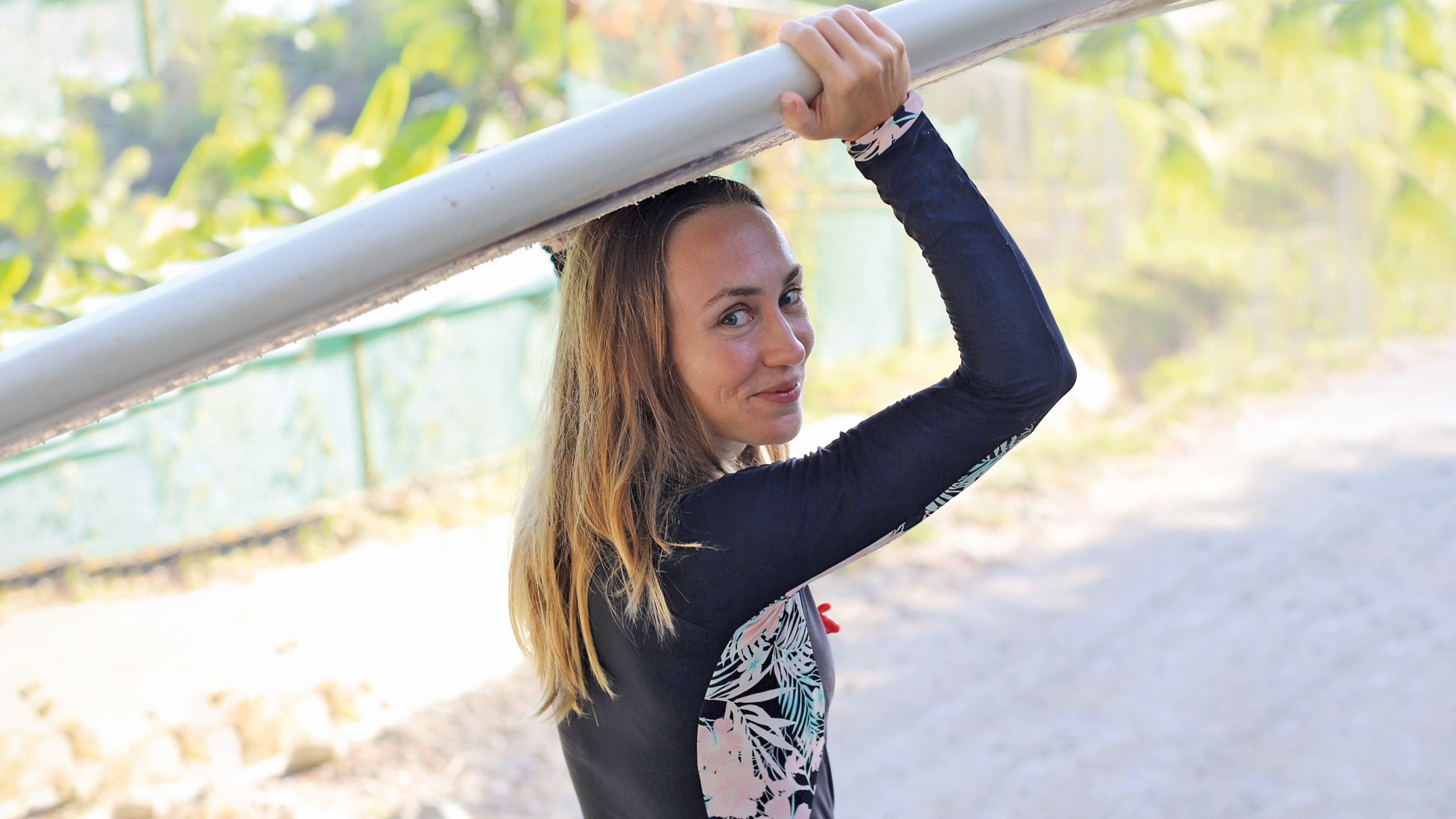 Eine Frau hält ein Surfbrett über ihren Kopf