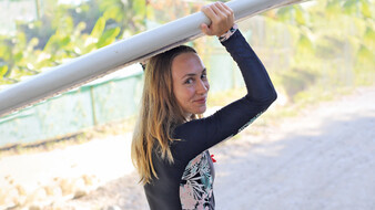 Eine Frau hält ein Surfbrett über ihren Kopf