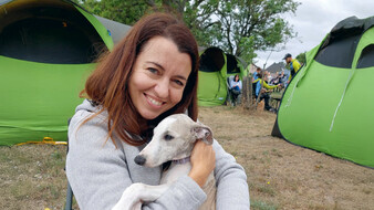 Eine braunhaarige Frau umarmt einen Hund auf einem Campingplatz