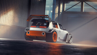 Ein orange-weißes Auto mit großem Heckspoiler steht in einer Halle