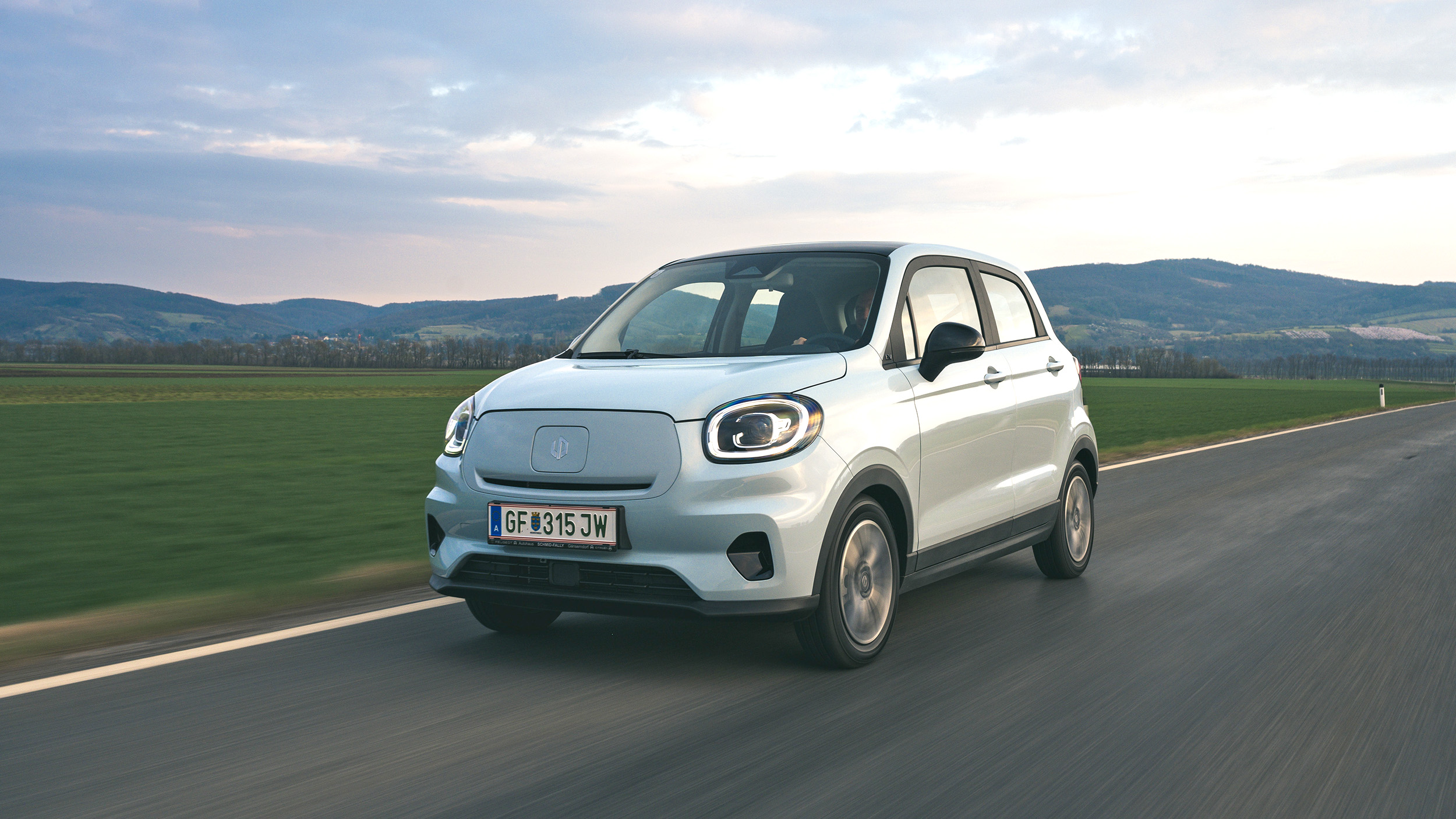 Der blaue Elektro-Kleinstwagen Leapmotor T03 fährt über eine Landstraße.