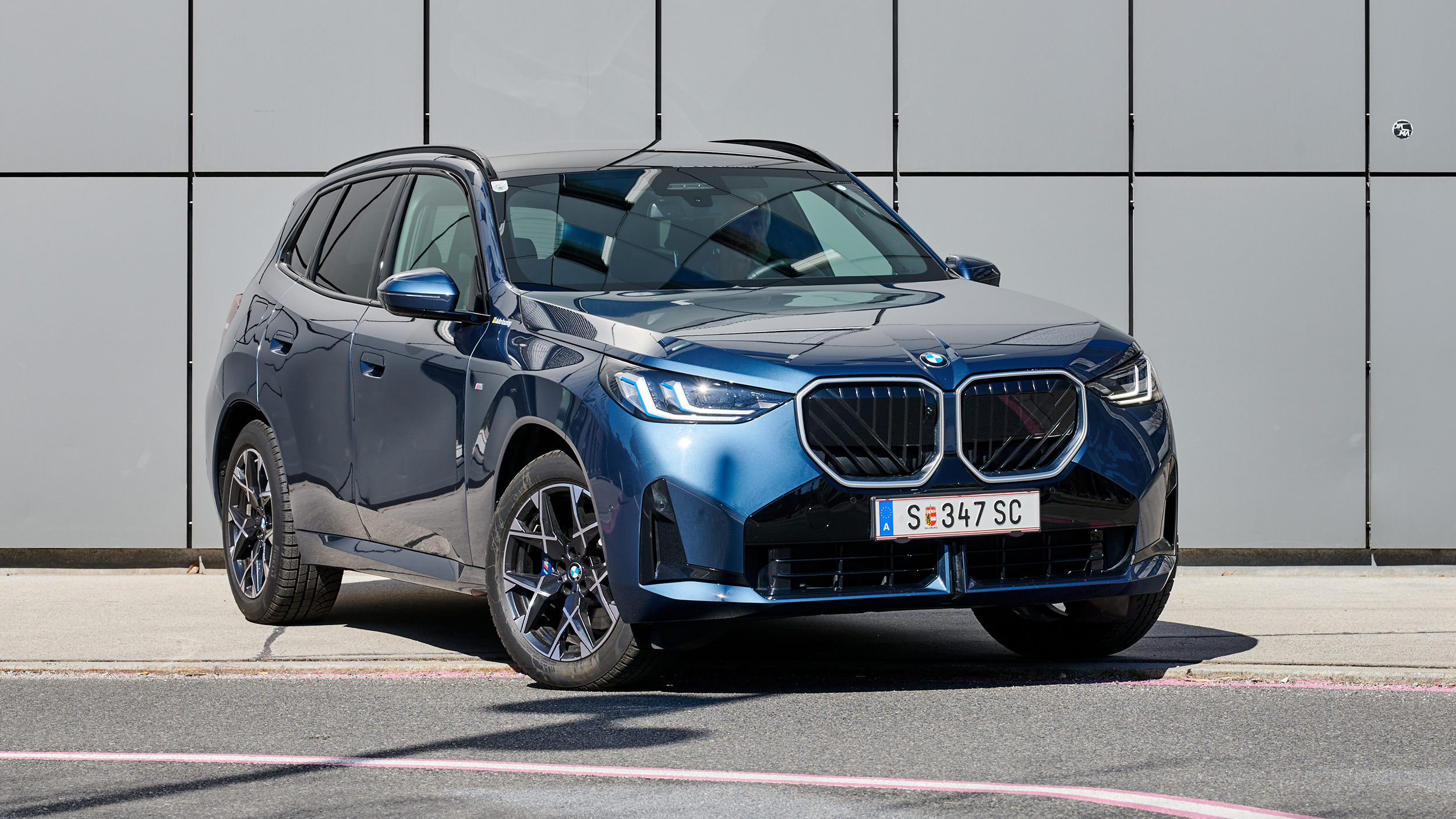Großes, blaues SUV vor einer grauen Wand