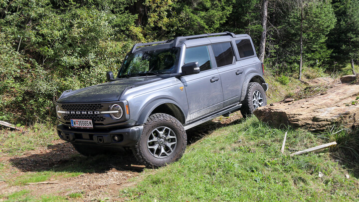 Ein grauer Geländewagen auf einer Waldstraße