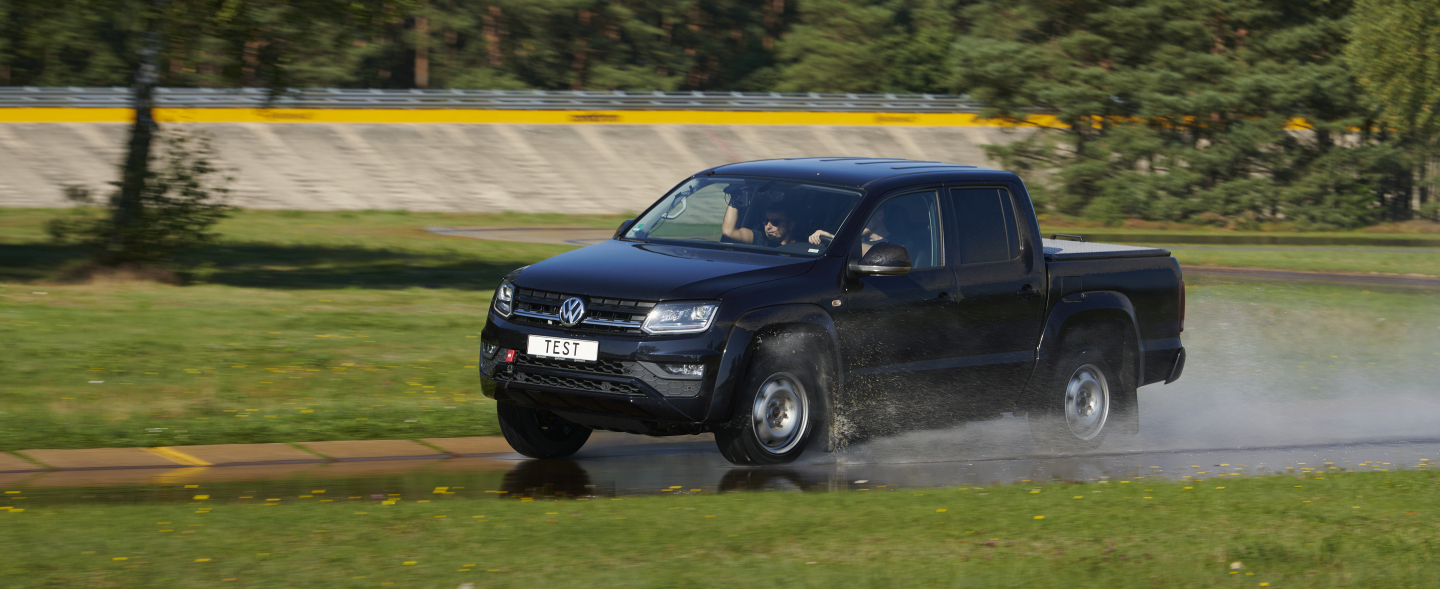 Ein schwarzer Pick Up fährt auf nasser Fahrbahn.