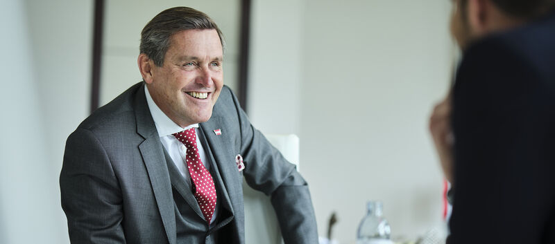 Portrait von Verkehrsminister Peter Hanke lachend im Interview.