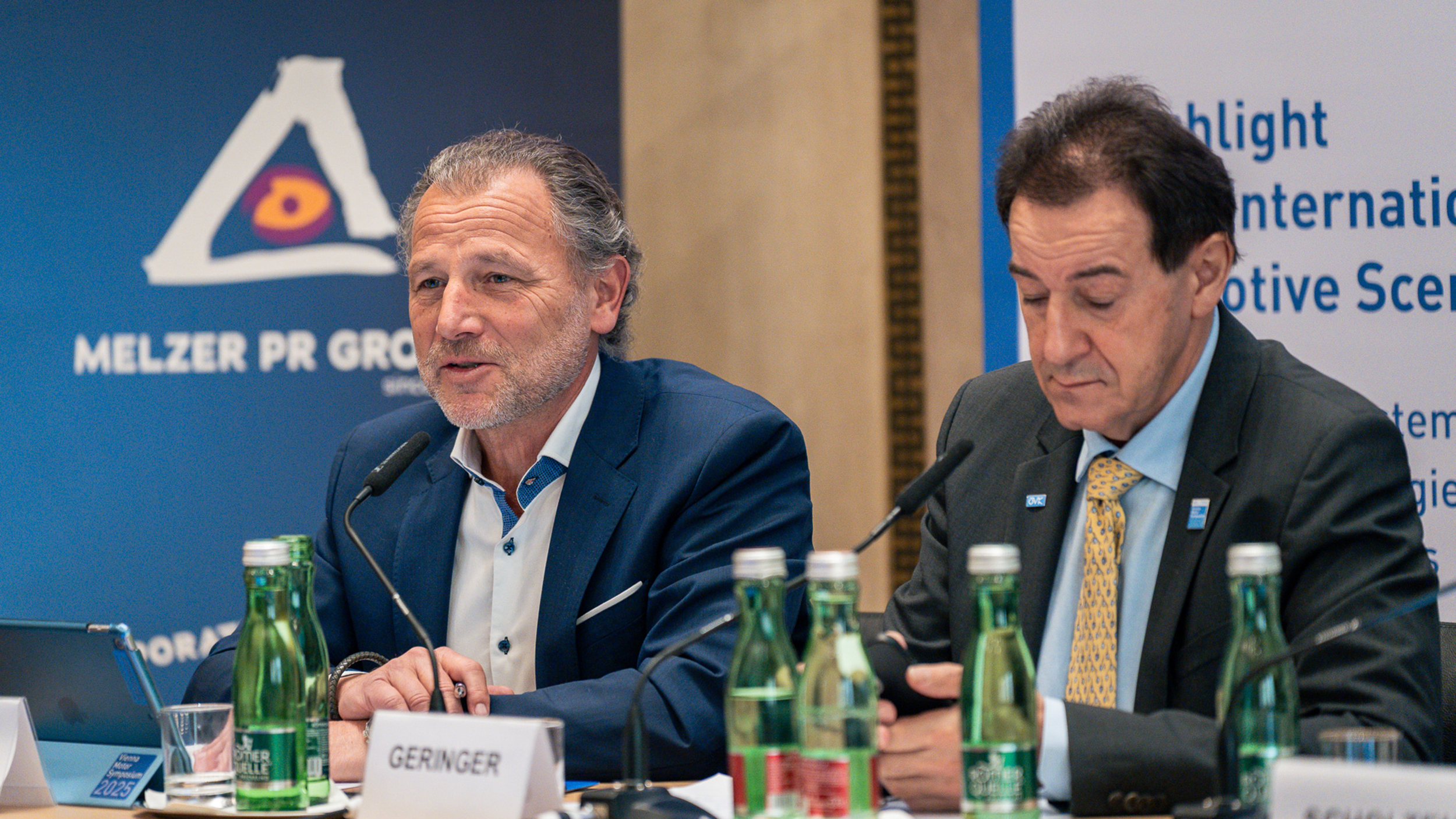 Zwei Männer in Anzügen geben eine Pressekonferenz