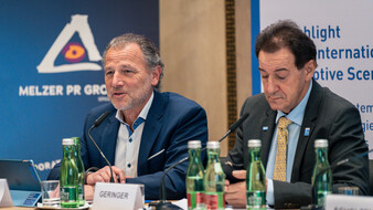 Zwei Männer in Anzügen geben eine Pressekonferenz