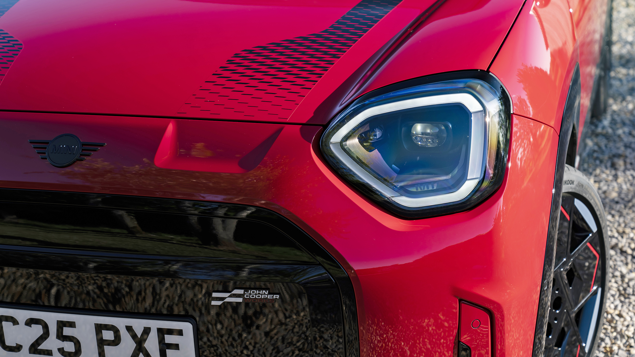 Scheinwerfer und schwarze Sportstreifen auf der Motorhaube eines roten Mini JCW Aceman