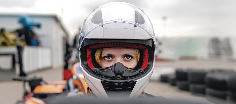 Frau mit weißem Sturzhelm im Cockpit
