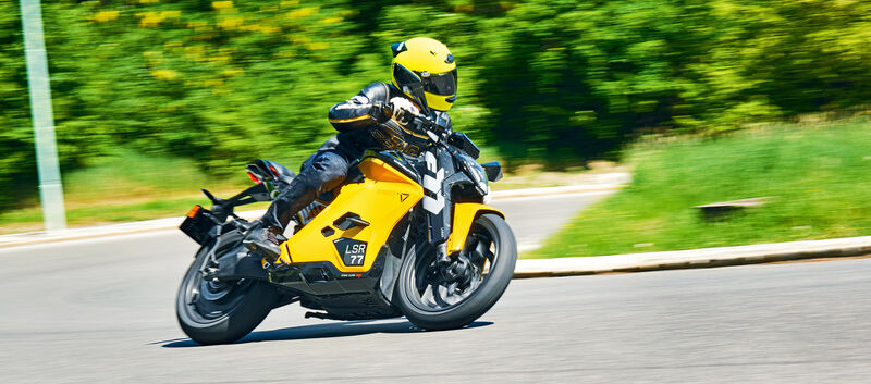 Gelbes Motorrad fährt in Schräglage um Kurve