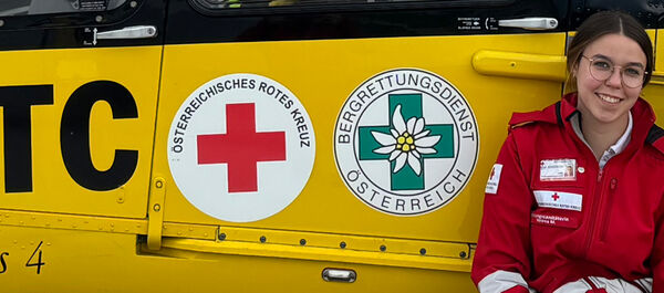 Eine junge Frau in Rotkreuz-Uniform und ein junger Mann in der Uniform der ÖAMTC-Flugrettung sitzen vor einem gelben Hintergrund. Auf diesem erkennt man den Schriftzug ÖAMTC, Christophorus, sowie die Logos der Bergrettung und des Roten Kreuzes.
