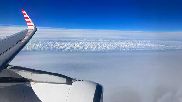 Blick auf den Himmel vom Flugzeug aus. Man sieht leicht die Tragfläche.