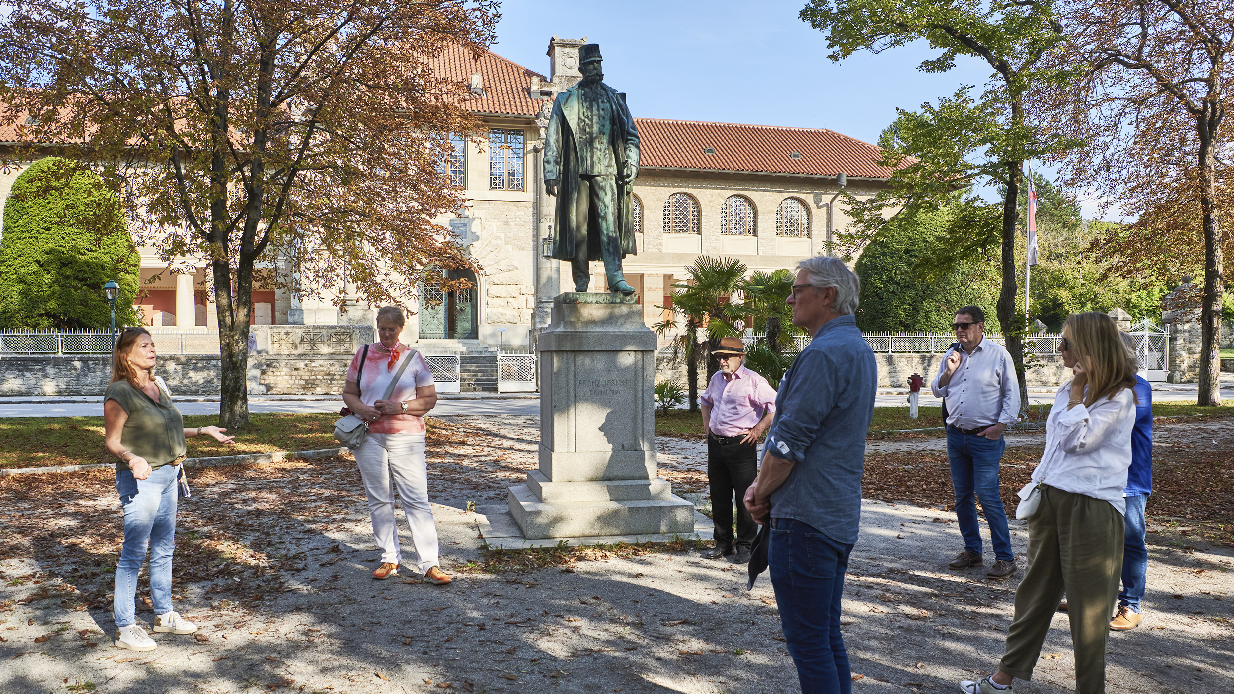 Vor dem Museum ist im Kurpark ein Denkmal von Kaiser Franz Joseph aufgestellt. Parkbesucher betrachten es.