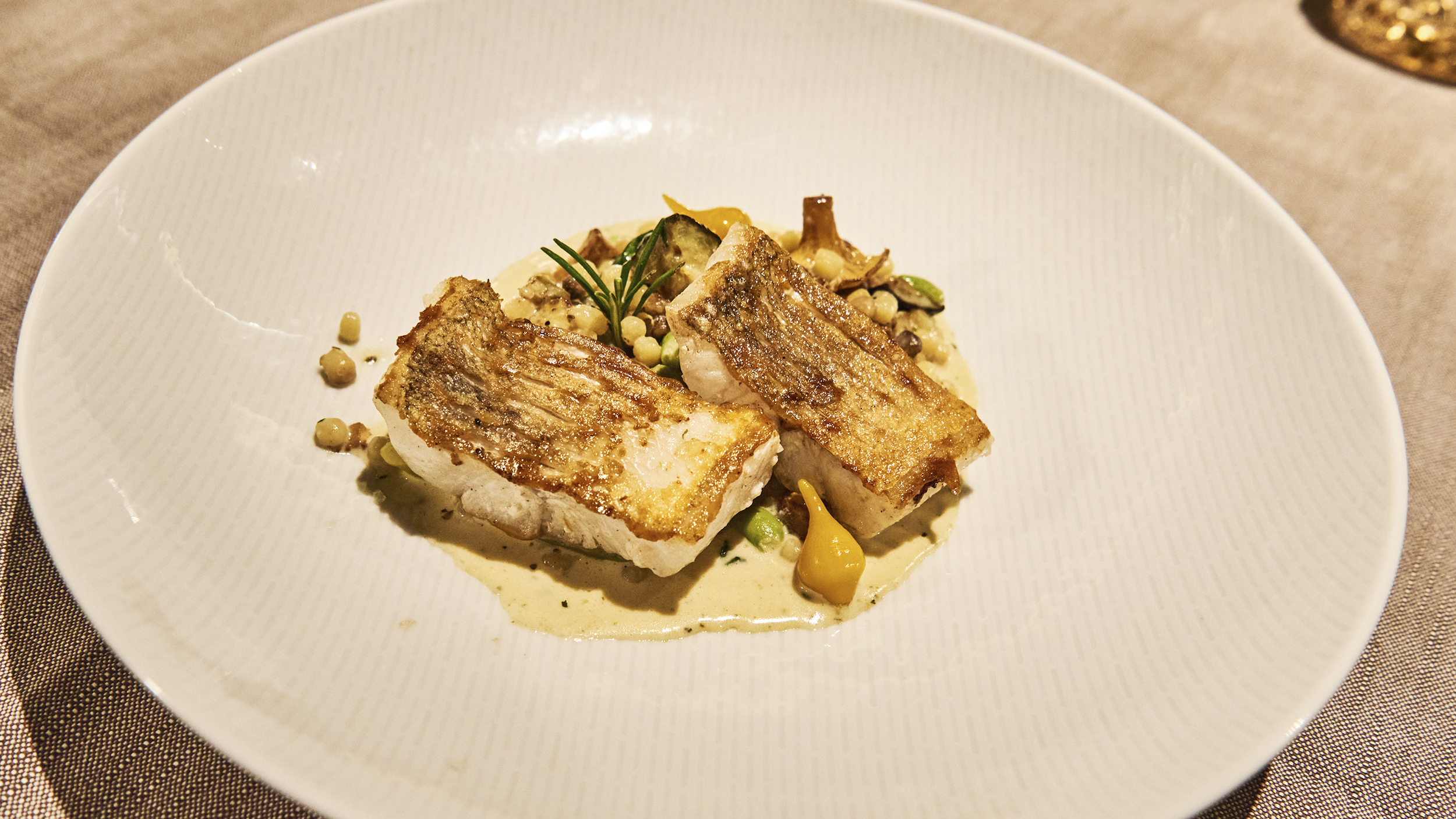 Ein Teller mit auf der Hautseite gebratenen Fischfilets.