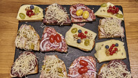 Eine Platte mit zwölf bunt belegten Brötchen.
