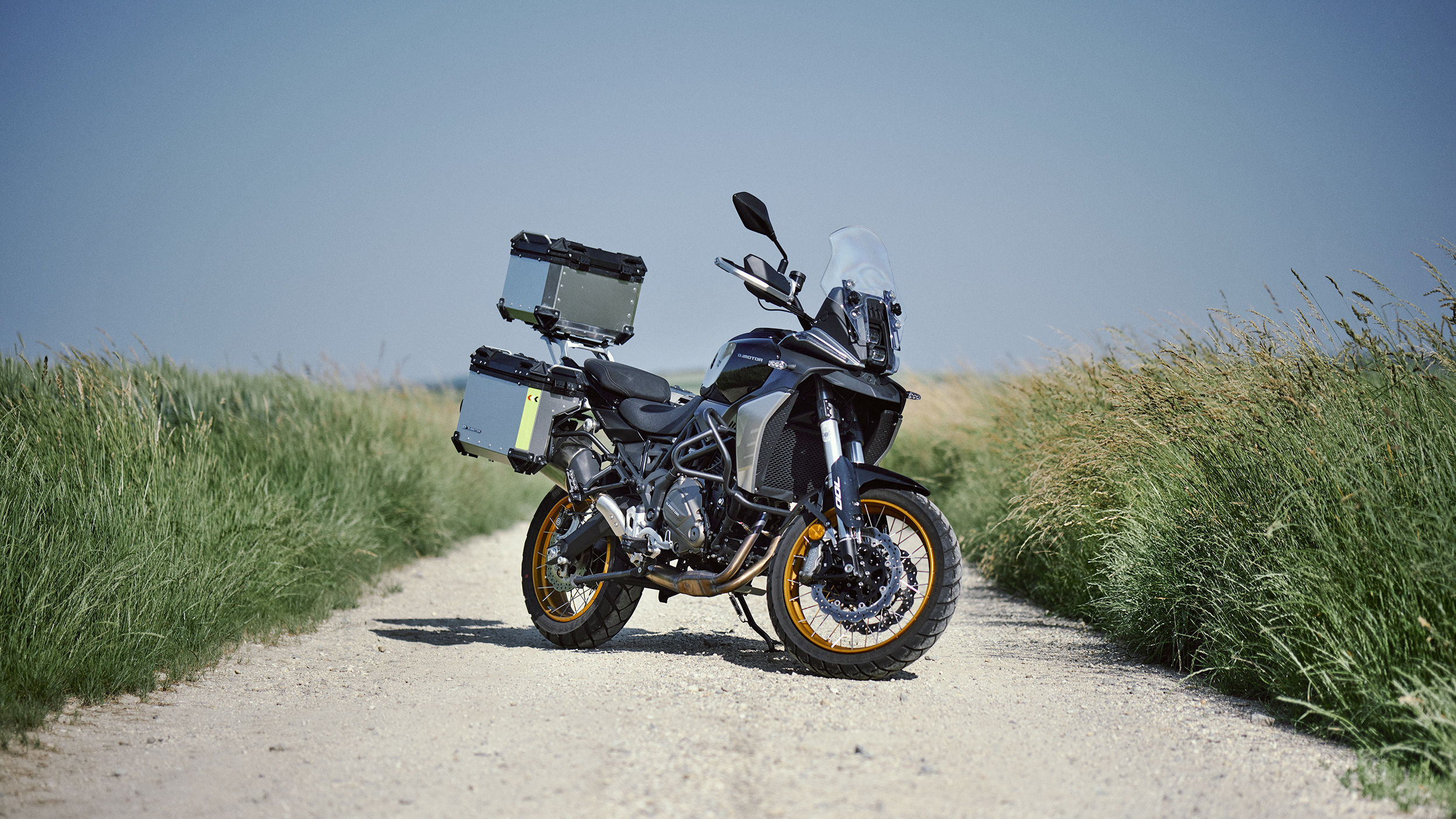 Die Mittelklasse Reiseenduro QJ SRT 700 SX mit drei am Heck montierten Alu-Koffern von schräg vorne hinten fotografiert.