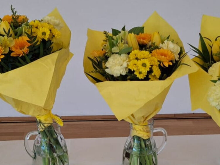 Gelbe Blumen Das Foto zeigt fünf Blumensträuße mit gelbem Geschenkpapier umwickelt. Die Blumen selbst sind ebenfalls gelb und orange.