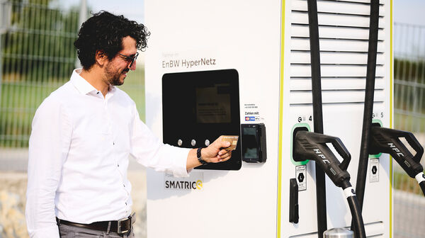 Ein Mann in weißem Hemd zahlt mit Kreditkarte an einer E-Ladesäule