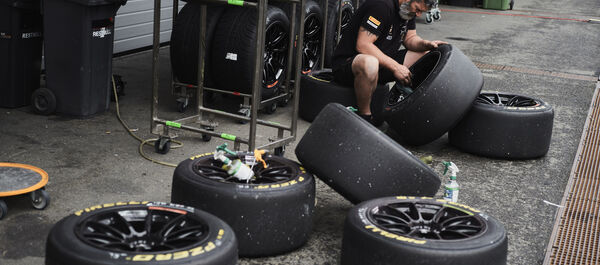 Eine Person sitzt zwischen einzelnen Reifen und putzt die Felge eines solchen.