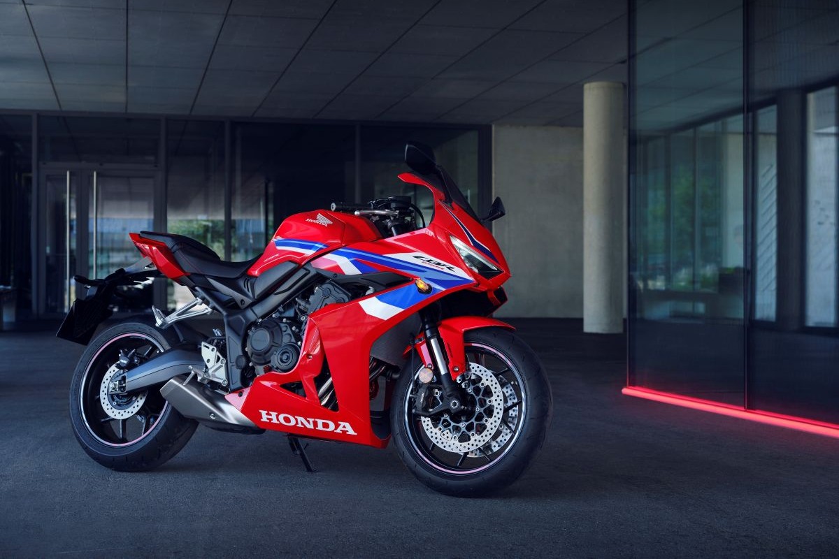 Das Foto zeigt ein Rot-Blaues Motorrad, das vor einem Gebäude steht.