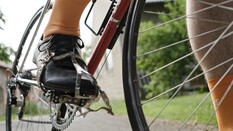 Auf dem Bild sieht man in Großaufnahme den Fuß eines Radfahrers mit schwarzen Schuhen.