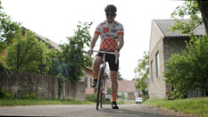 Auf dem Bild sieht man einen Radfahrer im weiß orangenen fahrraddress in einer Kellergasse.