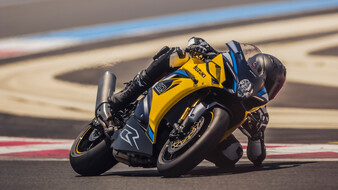 Ein gelbes Motorrad fährt auf einer Rennstrecke durch die Kurve