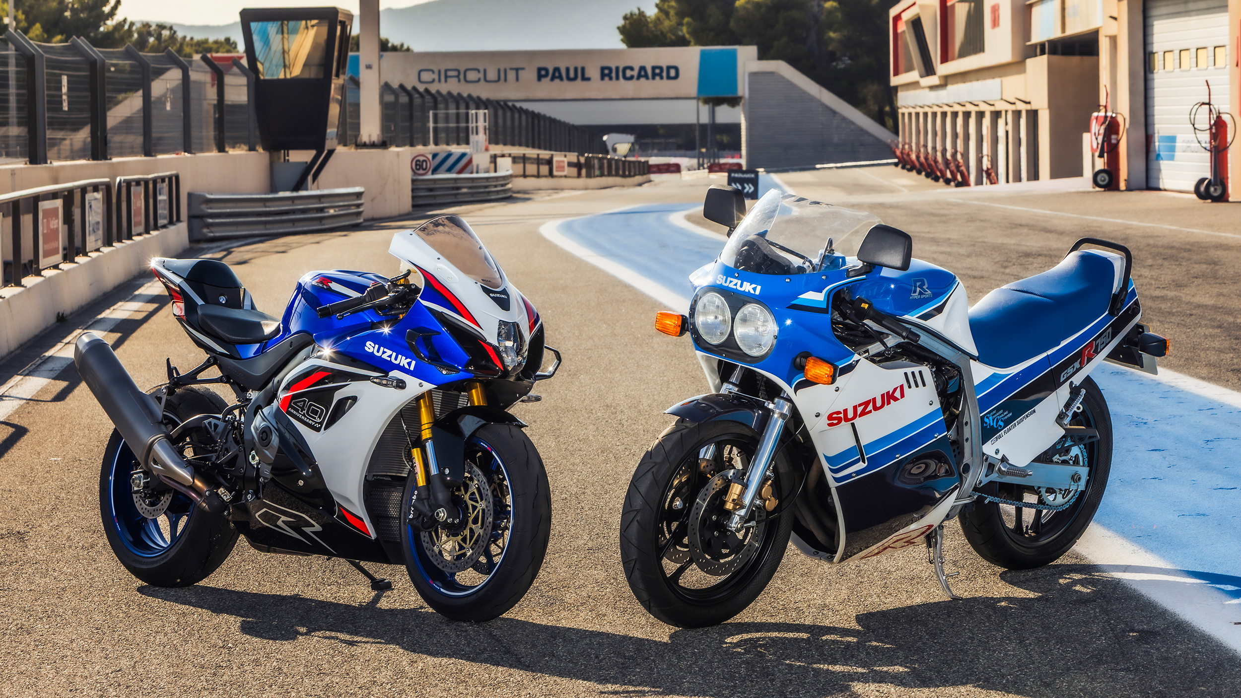Ein modernes und ein altes Motorrad stehen in einer Boxengasse nebeneinander