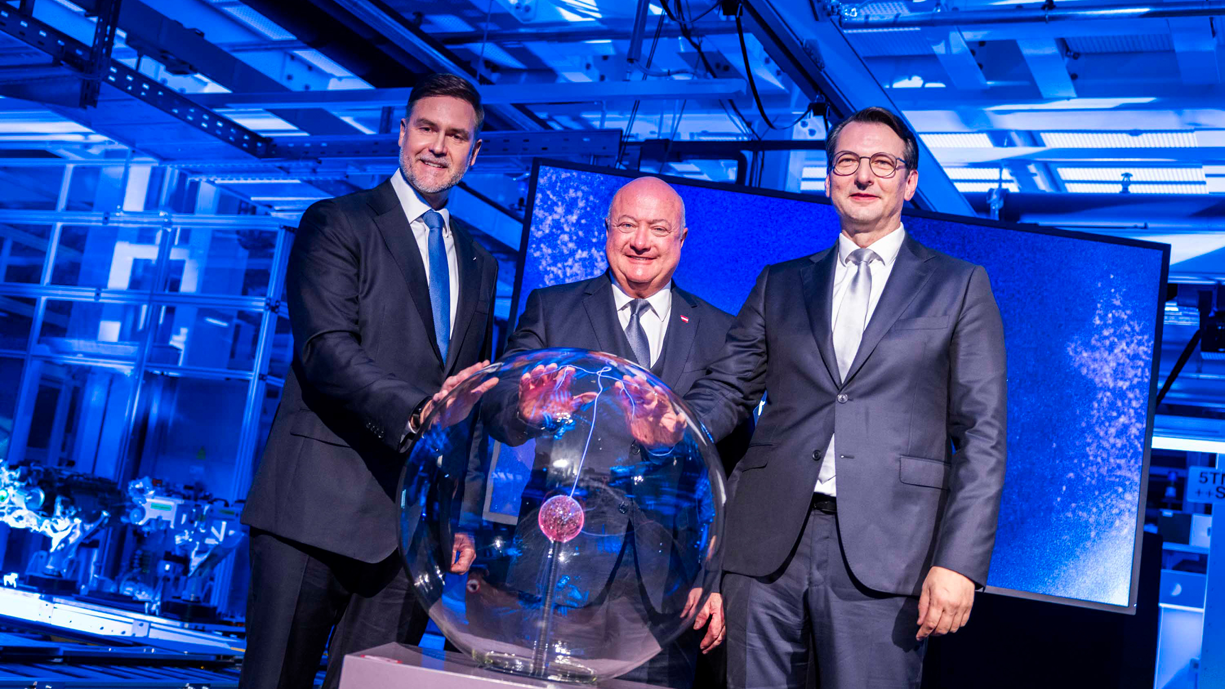 Drei Männer im Anzug legen ihre Hände auf eine Glaskugel