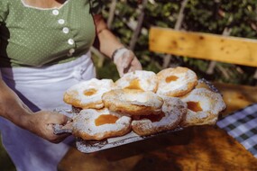 Die beliebten Salzburger Bauernkrapfen gibt es sowohl pikant als auch süß mit Marmelade. Das Foto zeigt einen großen Teller auf dem sieben Bauernkrapfen mit Marmelade liegen.