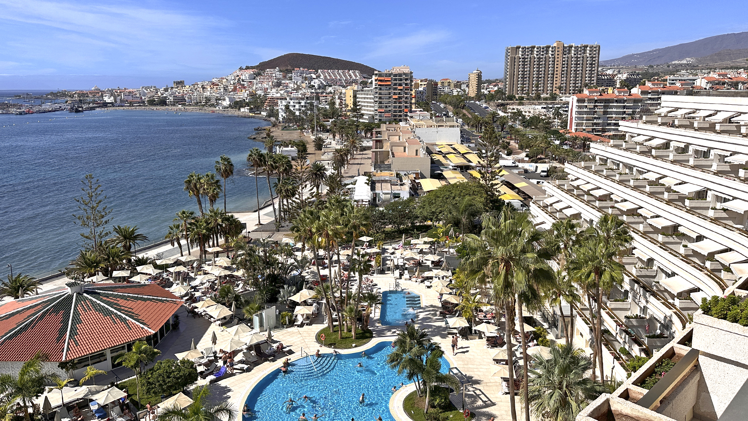 Blick vom Hotelbalkon auf Pools und Meer.