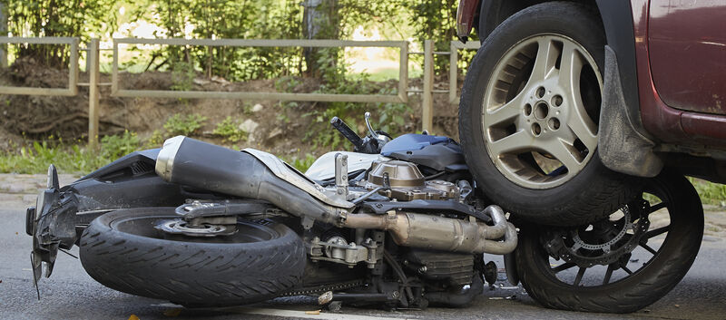 Ein Motorrad liegt unter dem Reifen eines Autos