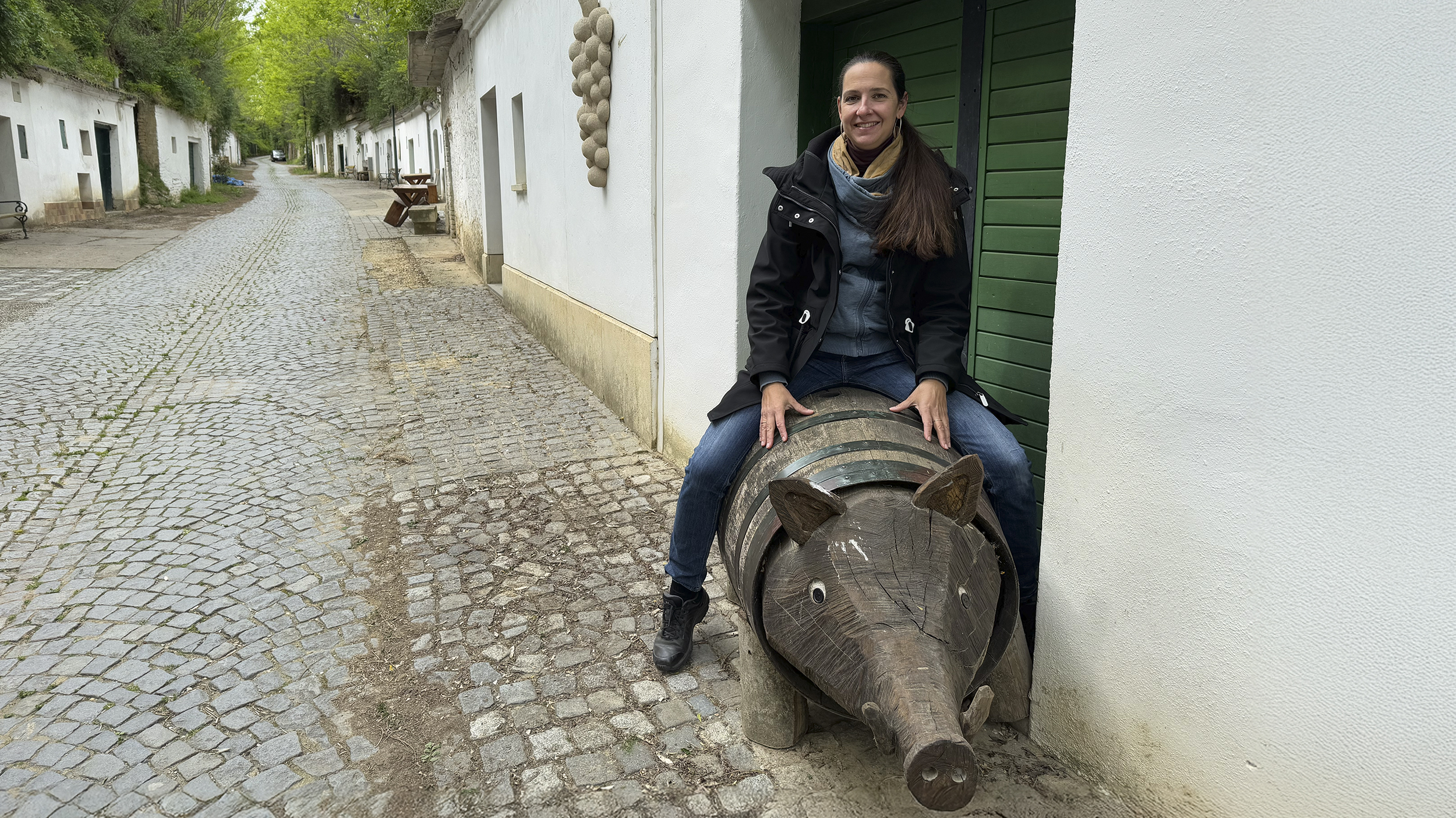 Redakteurin Conny sitzt auf einem Holzschwein in der Kellergasse.