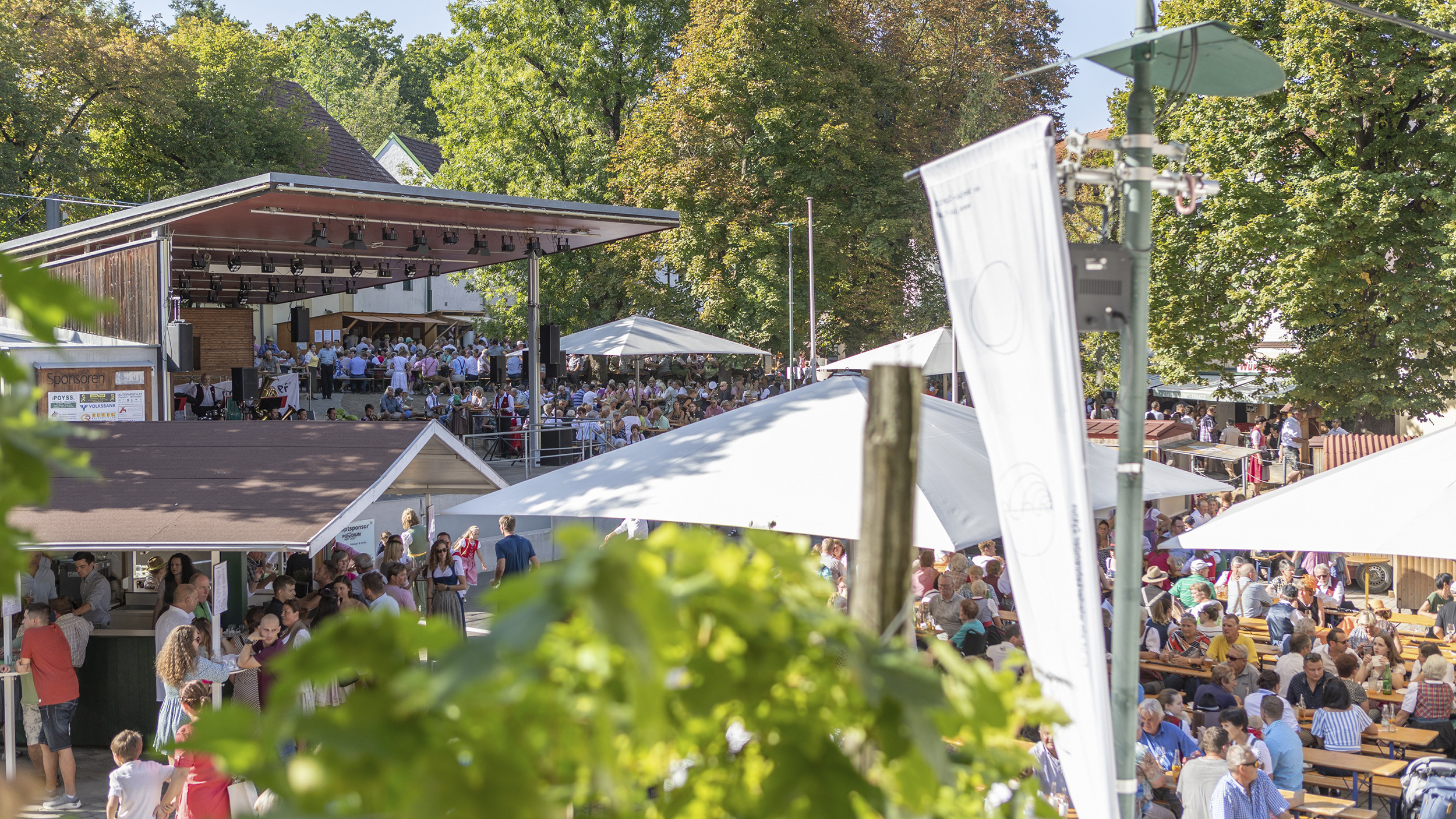 Viele Leute sind beim Winzerfest und sitzen auf Heurigenbänken.