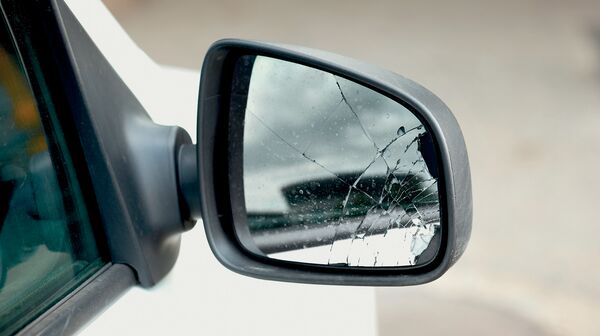 Der beschädigte Außenspiegel eines weißen Autos