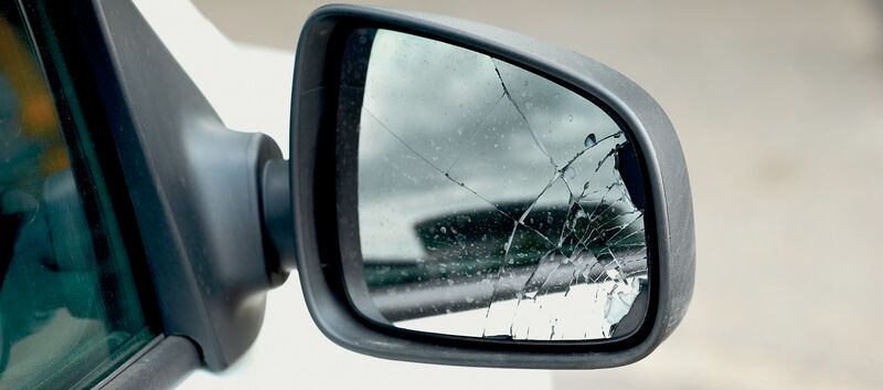 Der beschädigte Außenspiegel eines weißen Autos
