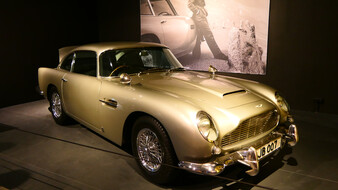 Ein silberner Aston Martin DB5 mit einer Leinwand im Hintergrund