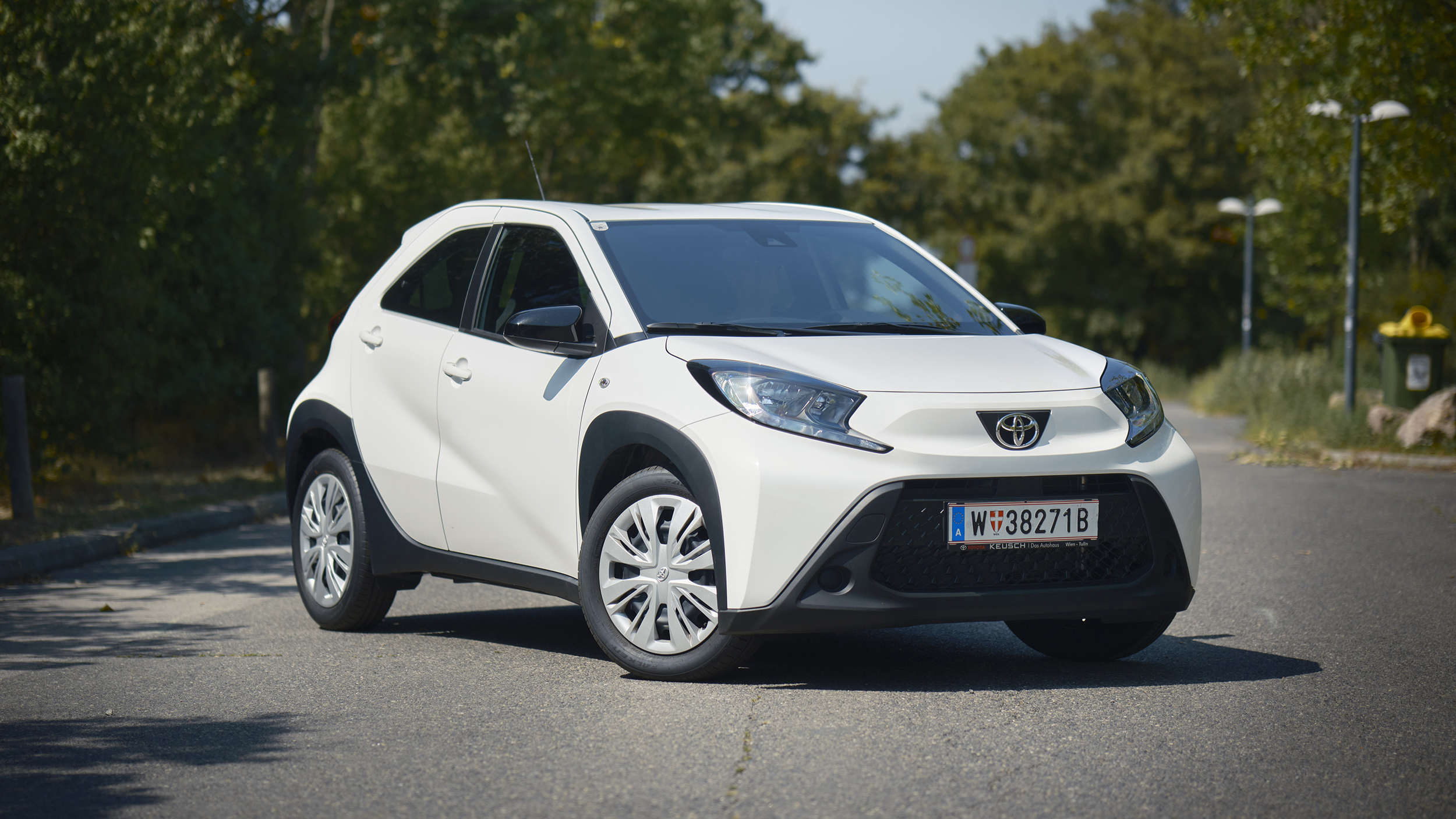 Ein weißer Toyota Kleinwagen steht auf einer Straße