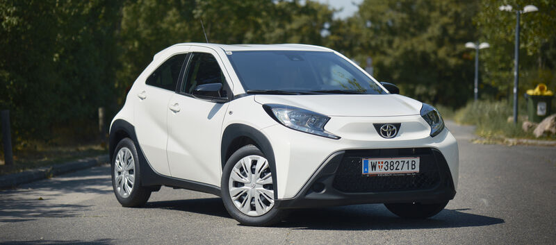 Ein weißer Toyota Kleinwagen steht auf einer Straße