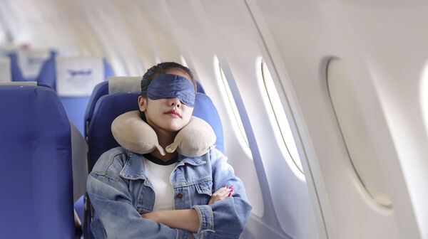 Frau schläft mit Schlafmaske in Flugzeug.