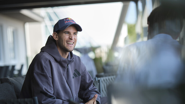 Der Ex-Tennisspieler Dominic Thiem mit Kappe und grauem Kapuzenpullover im Gespräch mit einem Journalisten.
